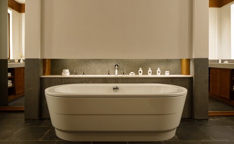 Freestanding stone bathtub in Amandayan Suite bathroom with illuminated shelf and dark wood panelling.