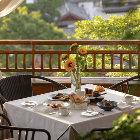 Breakfast table at Amandayan's China Pavilion with fresh flowers and morning light filtering through trees.