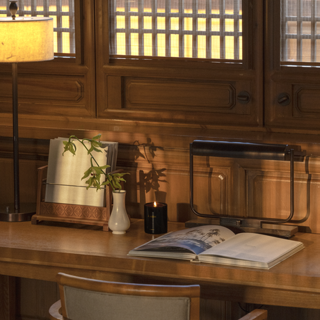 Wooden desk with desk lamp, decorative objects and open book in a courtyard suite at Amandayan, China.