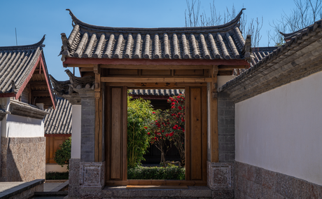 Courtyard entrance with traditional Chinese architecture at Amandayan, featuring curved tile roof and wooden doorway.