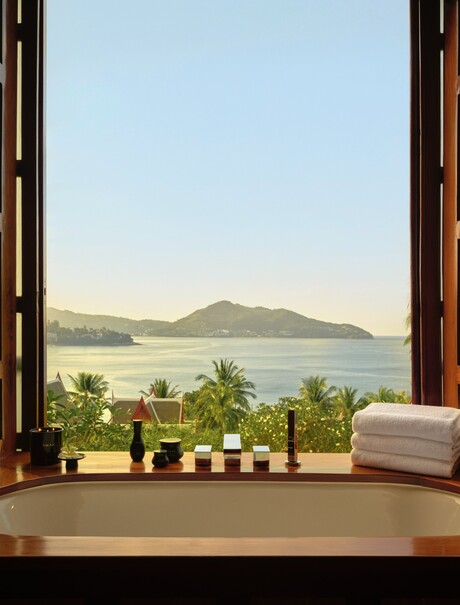 Amanpuri bathroom pavilion with view across coastal landscape through open wooden doors.
