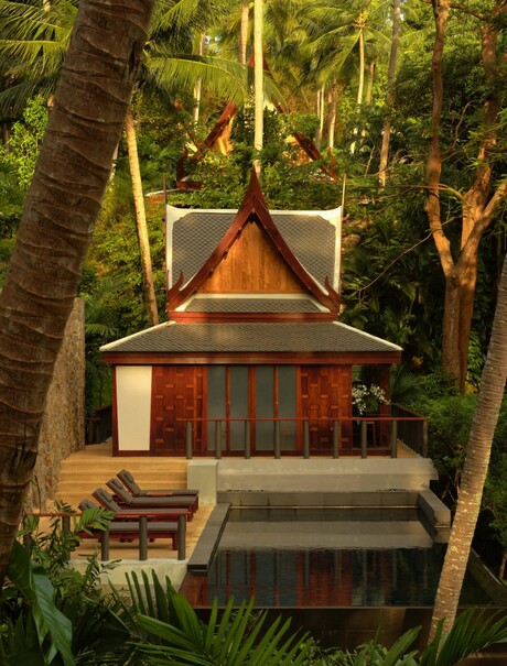 Spa treatment room at Amanpuri nestled amongst tall trees, with warm wood tones and a pitched roof design.