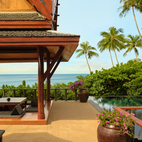 Amanpuri pavilion outdoor terrace with wooden eaves, sea views and palm trees in Thailand.