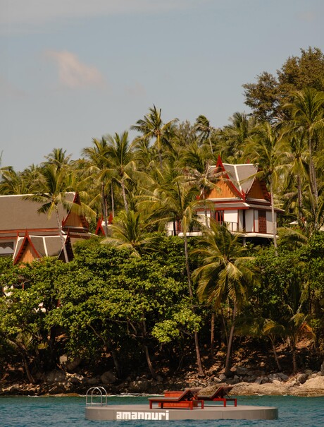 Amanpuri's ocean platform extends over the Andaman Sea, surrounded by tropical palms and coastal architecture.