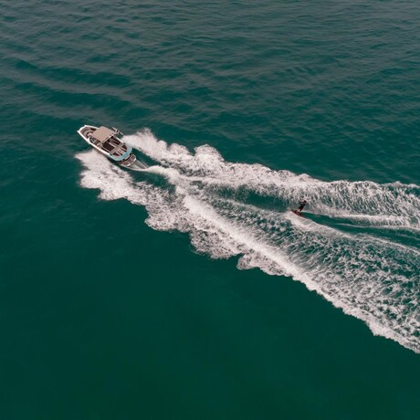 Wakeboarder carving across turquoise waters at Amanpuri, Thailand.