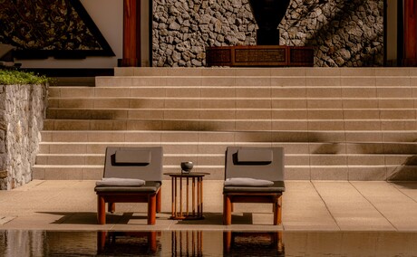 Amanpuri's pool terrace featuring wooden seating areas and calm water in Thailand.