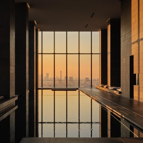 Indoor plunge pool at Aman Tokyo with gridded window overlooking the city at dusk.