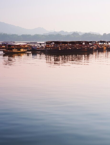 Wooden boats moored on still water at dawn, Amanfayun, Hangzhou.