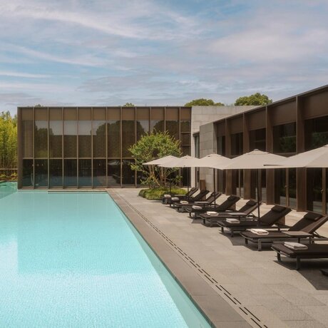 Amanyangyun spa pool surrounded by loungers and dark wooden pavilions in China.