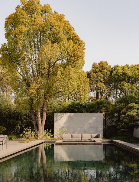 Villa exterior with reflecting pool at Amanyangyun, China, framed by golden trees.