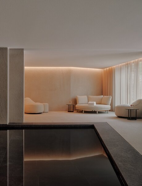 Indoor swimming pool at Aman Rosa Alpina with warm ambient lighting and minimalist design, Italy.
