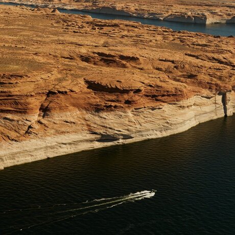 Aerial view of a speedboat on Lake Powell with red-rock cliffs at Amangiri.