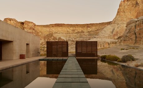 Reflection pool at Amangiri spa with wooden doors and sandstone cliff backdrop, USA.