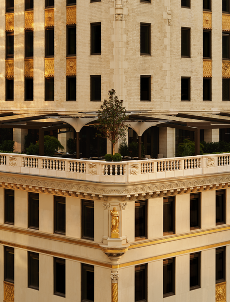 Exterior view of Aman New York's garden terrace with classical stone balustrade and arched colonnade.
