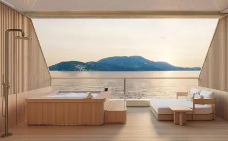 Spa treatment room at Amangati with minimalist wooden furniture and a panoramic window overlooking calm blue waters and distant mountains.