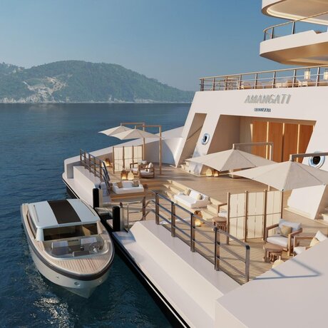 Aman at Sea lounge deck with tender boat and coastal mountains beyond.
