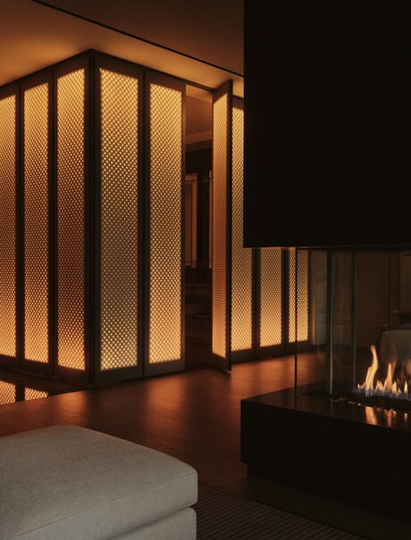 Grand Suite bedroom with illuminated wooden partition screen and fireplace at Aman New York.