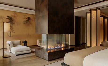 Grand Suite at Aman New York with fireplace, seating area and bed.
