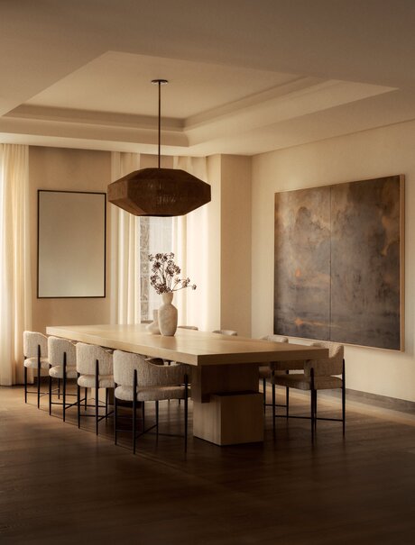 Three-bedroom penthouse dining room at Aman New York with wooden table, pendant light, and gallery walls.