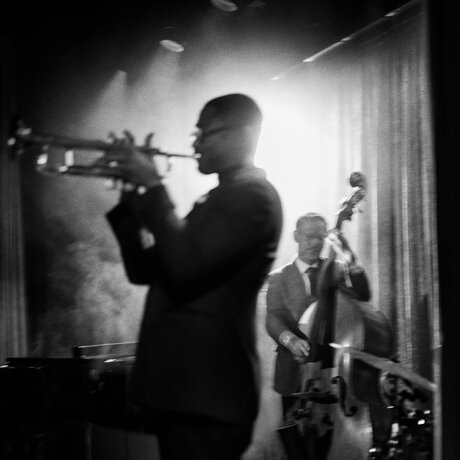 Jazz musician playing trumpet with band members at Aman New York.