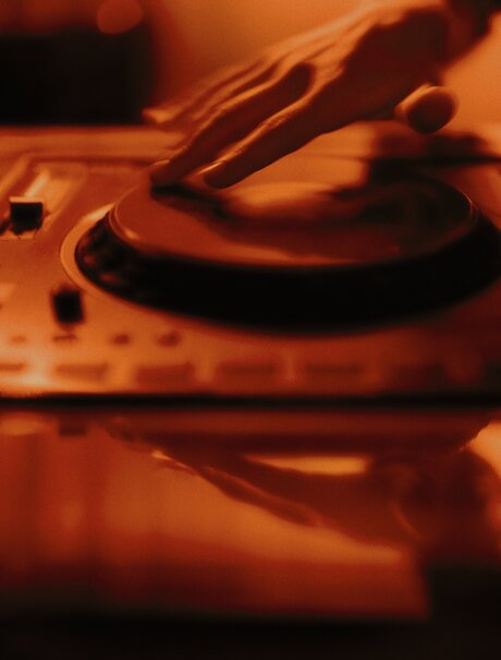 アマン ニューヨークのジャズクラブで、DJ機材のターンテーブルが暖色に照らされている。