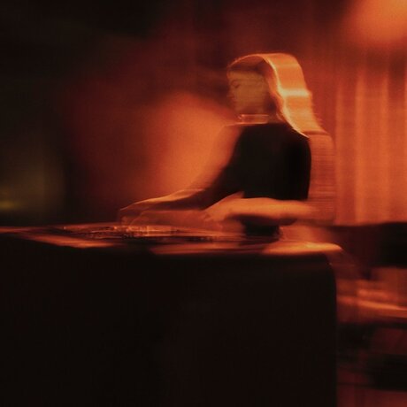 DJ performing at Aman New York's jazz club, bathed in warm amber lighting.