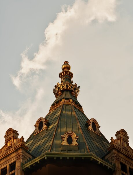 Ornate gilt crown detail of Aman New York's exterior against cloudy sky.