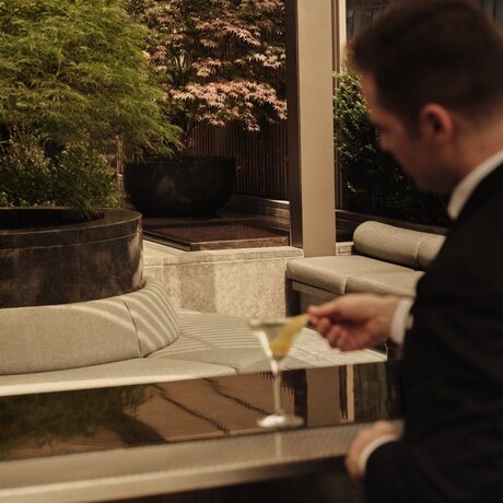 Man reviewing plans on terrace at Aman New York with city views beyond.