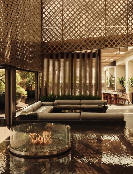 Terrace at Aman New York with wooden screens, low seating, and fireplace glowing at dusk.