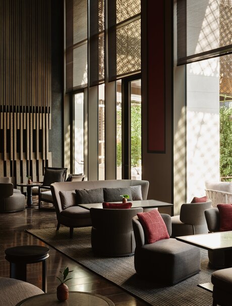 Aman New York lounge with floor-to-ceiling windows, contemporary seating, and natural light.