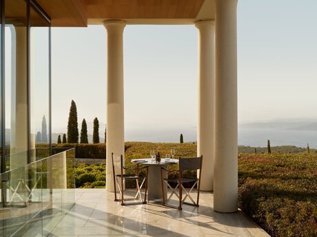 Dining venue at Amanzoe resort with terrace overlooking the Aegean Sea and cypress trees.