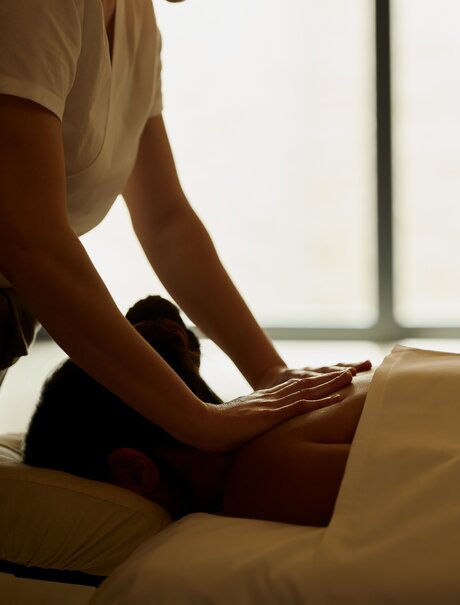 Therapist's hands administering a back massage during a wellness treatment at Amanzoe resort in Greece.