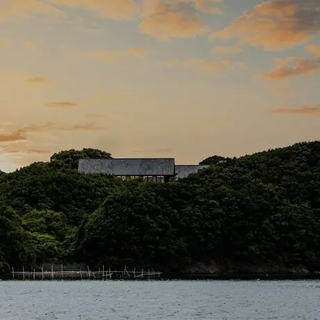Coucher de soleil sur la baie avec le resort Amanemu visible sur la côte boisée.
