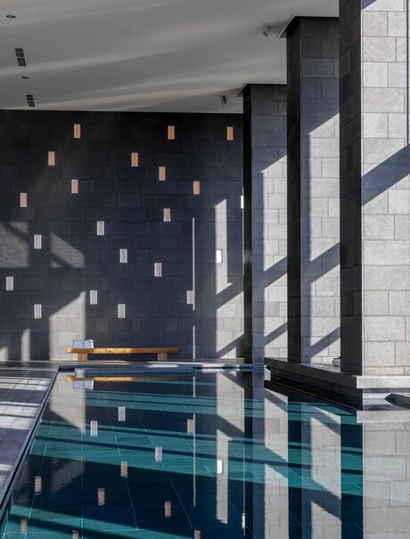 Aman Tokyo spa swimming pool with teal water and suspended lighting.
