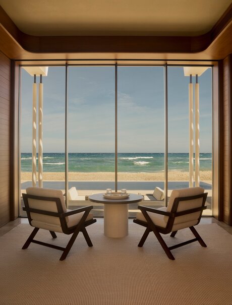 Beachfront casita at Amanvari with two wooden chairs facing expansive ocean views through floor-to-ceiling windows.