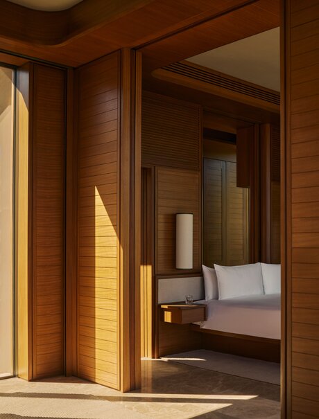 Wooden-framed entrance to an Estuary Casita at Amanvari, Mexico, with warm sunlight streaming across the threshold and a glimpse of the principal bedroom beyond.