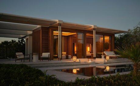 Estuary Casita exterior at dusk, illuminated wooden pavilion reflected in still water at Amanvari, Mexico.