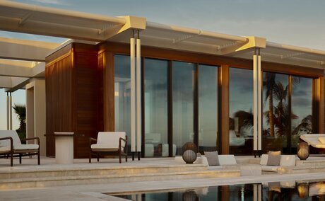 Estuary Casita exterior at Amanvari, Mexico, with wooden and glass pavilion overlooking water at dusk.