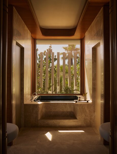 Bathroom in a Horizon Casita at Amanvari, Mexico, with a deep soaking tub positioned beneath a window framing views of desert landscape and cacti.