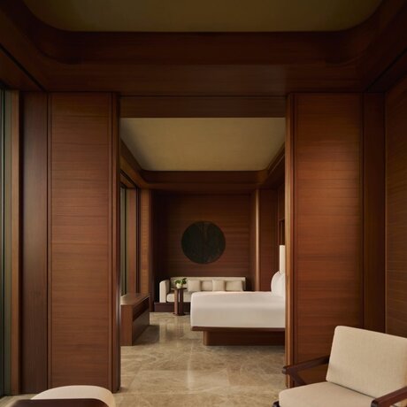 Principal bedroom at Amanvari with warm terracotta walls, contemporary furnishings, and connected ensuite bathroom.
