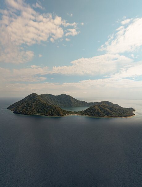 Drone view of Satonda Island's volcanic landscape rising from calm waters at Amanwana, Indonesia.
