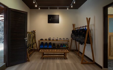 Dive centre interior at Amanwana with wooden benches, diving equipment and tools displayed on walls.