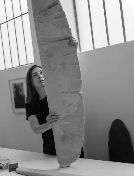 Studio portrait of artist Despina Flessa with large stone sculpture at Amanzoe, Greece.