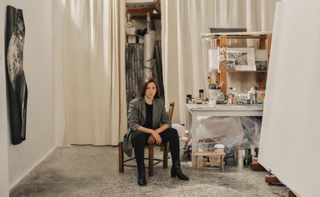 Studio portrait of Despina Flessa at Amanzoe art exhibit in Greece, seated amongst sculptural works.