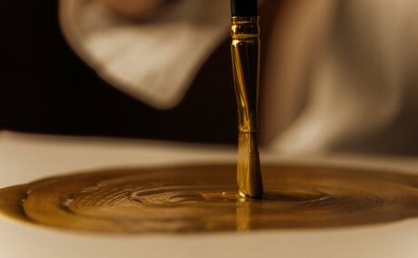 Golden oil pouring onto wooden surface at Amanzoe, Greece.