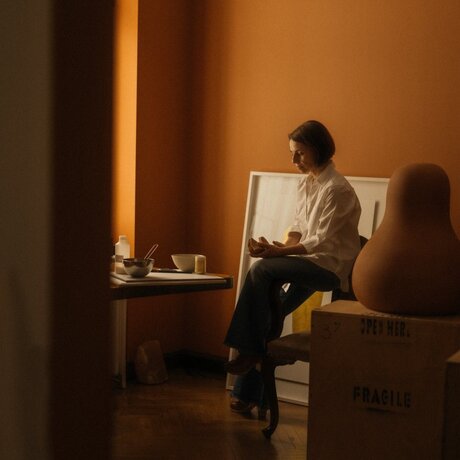 Nikomachi Karakostanoglou seated with laptop at Amanzoe, Greece, studio portrait.