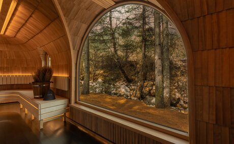 Wooden sauna interior at Amankora's Paro Lodge with arched ceiling and large window overlooking forest.