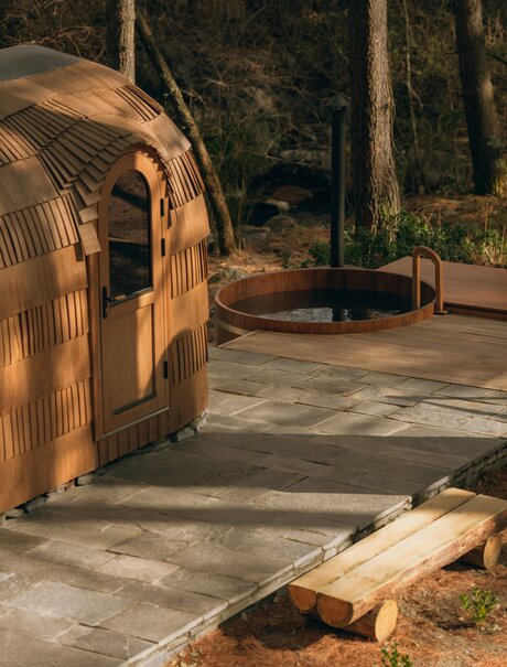 Wooden sauna barrel at Amankora's Paro Lodge, with stone pathway and forest surroundings.