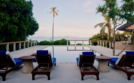 Villa pool terrace at Amanpulo, Philippines, with loungers overlooking calm water at dusk.