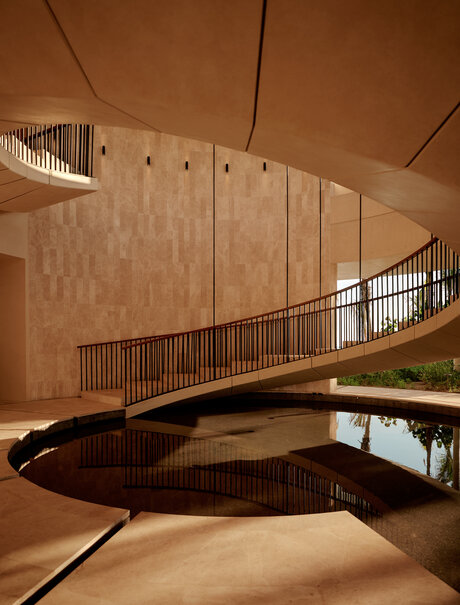 Curved wooden staircase at Amanvari, Mexico, with warm terracotta walls and minimalist design.
